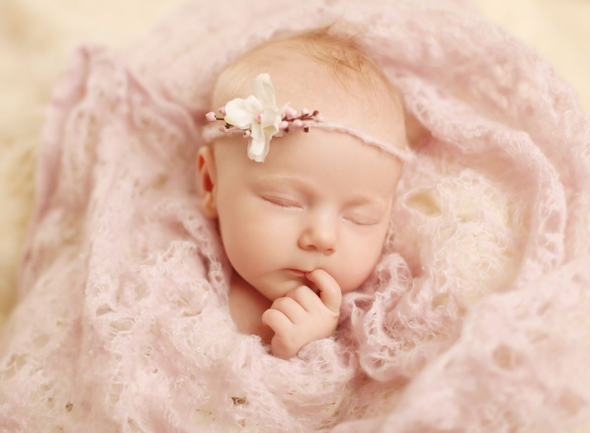 Roztomilý detail hlavičky novorozeného miminka s prstem v pusince