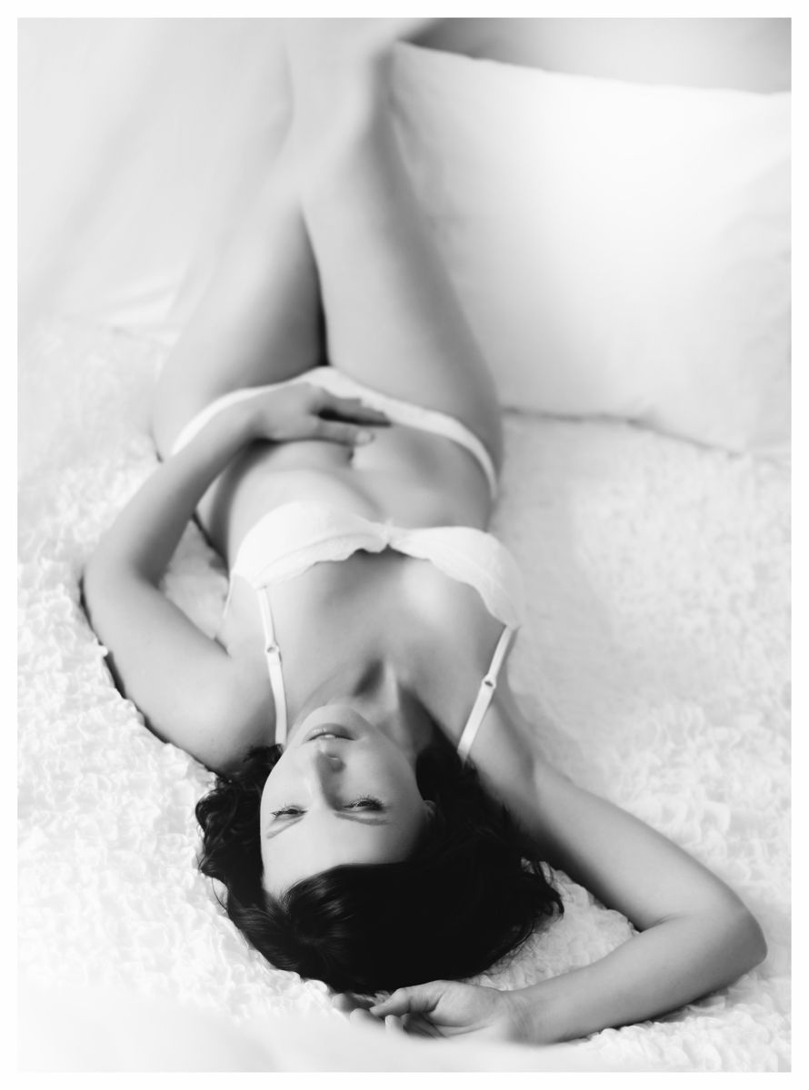 Černobílá zasněná boudoir fotografie brunetky v bílém prádle v posteli z nadhledu | © Fotoprome.cz