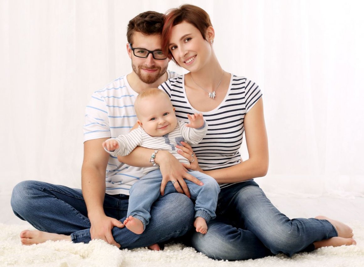 Rodinné focení mladých rodičů s miminkem v náručí a pruhovaných tričkách v ateliéru